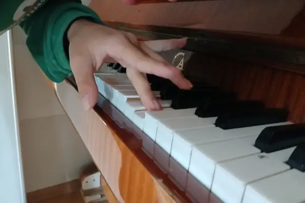 Dziecko grające na pianinie podczas zajęć muzycznych lub terapii muzycznej.